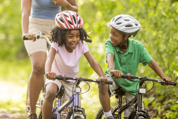 A family is going on a bike ride through the woods while on summer vacation.