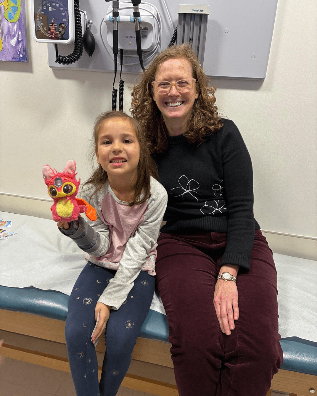 Female child and doctor post for a photo in a clinical room