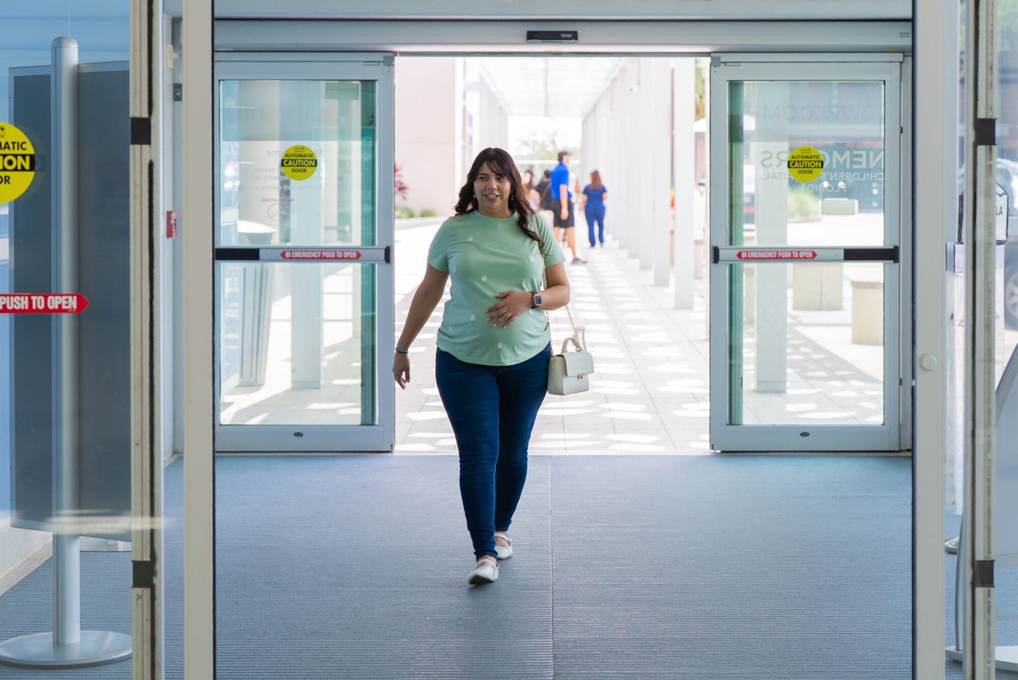 Pregnant woman walking through the front doors of a hospital for her first maternal fetal medicine visit