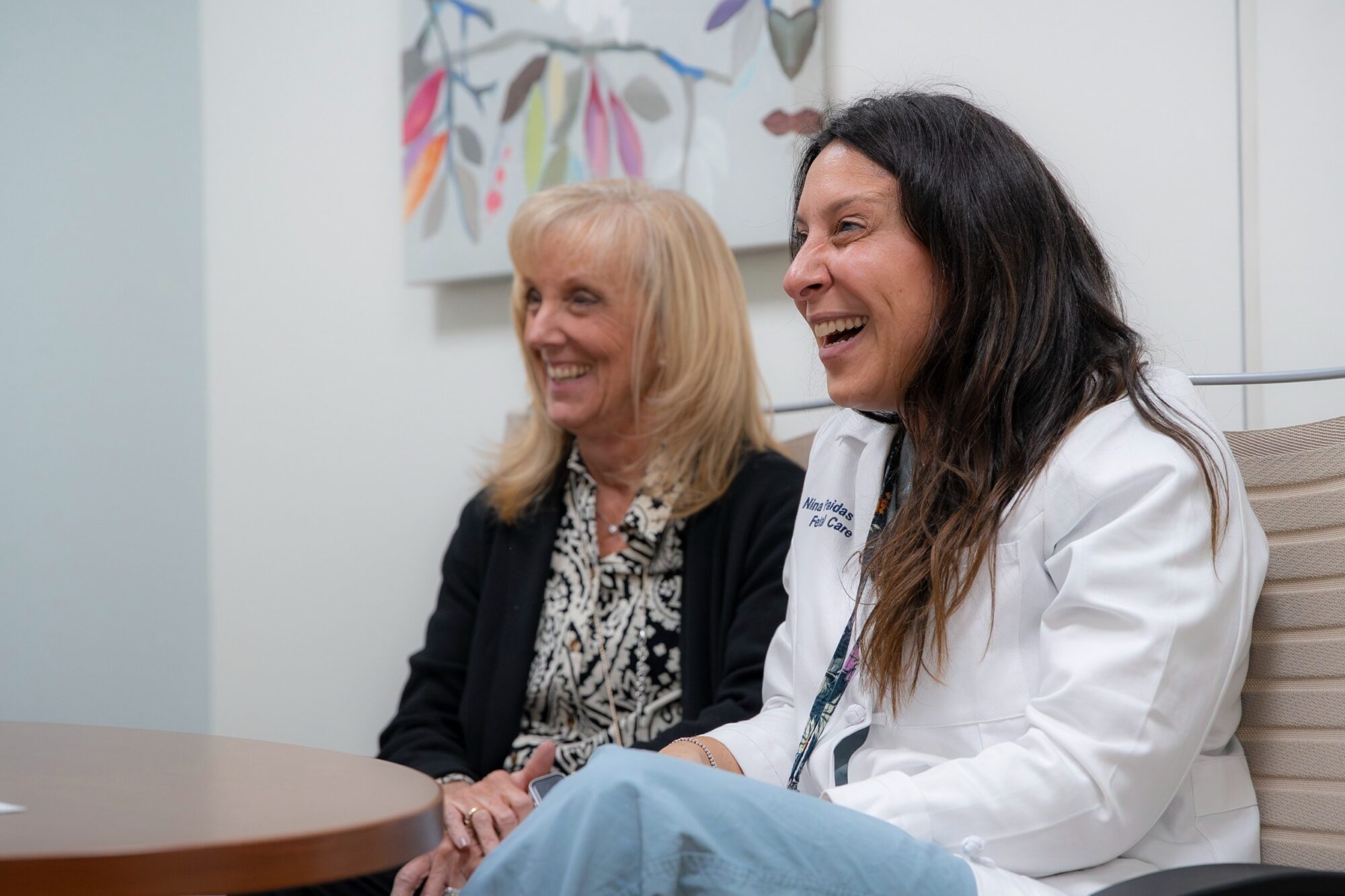 Maternal fetal care specialists sitting at a table and smiling as they meet with their patient.