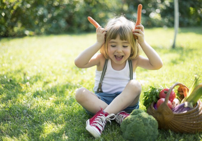 Cute child with a basket of organic vegetables