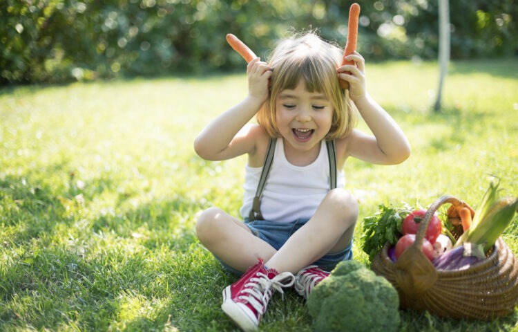 Cute child with a basket of organic vegetables
