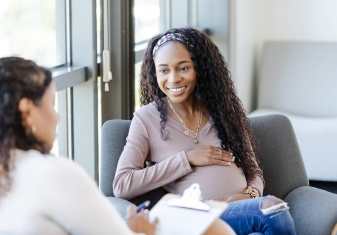 A woman smiles as she discusses her feeling with a doctor.