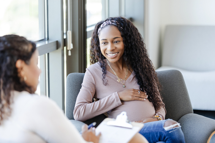 A woman smiles as she discusses her feeling with a doctor.