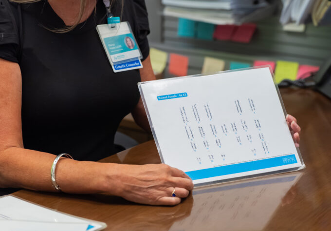 A closeup of a genetic counselor showing a karyogram to a patient during a prenatal genetic counseling consult.