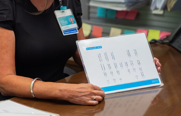 A closeup of a genetic counselor showing a karyogram to a patient during a prenatal genetic counseling consult.