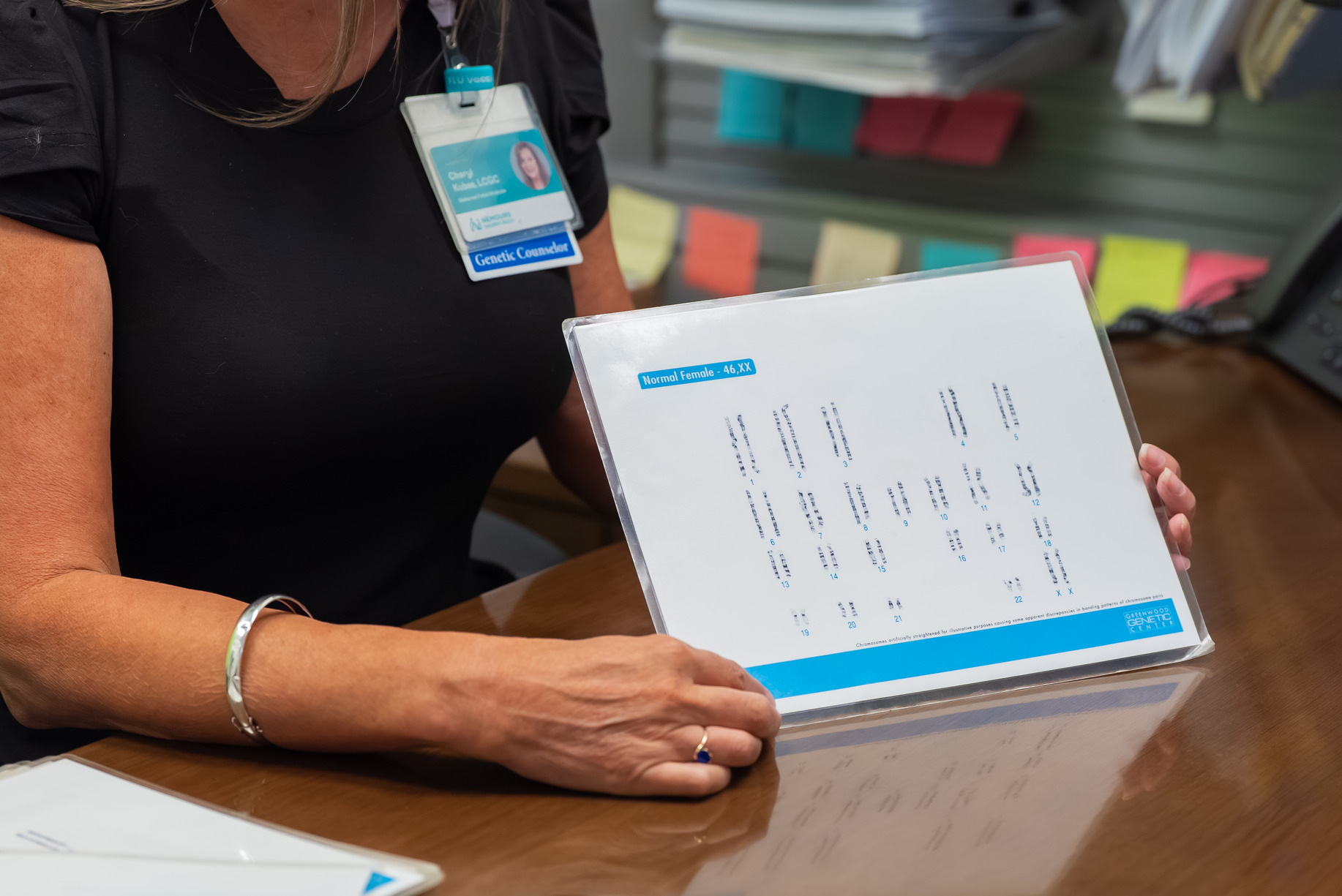 A closeup of a genetic counselor showing a karyogram to a patient during a prenatal genetic counseling consult.