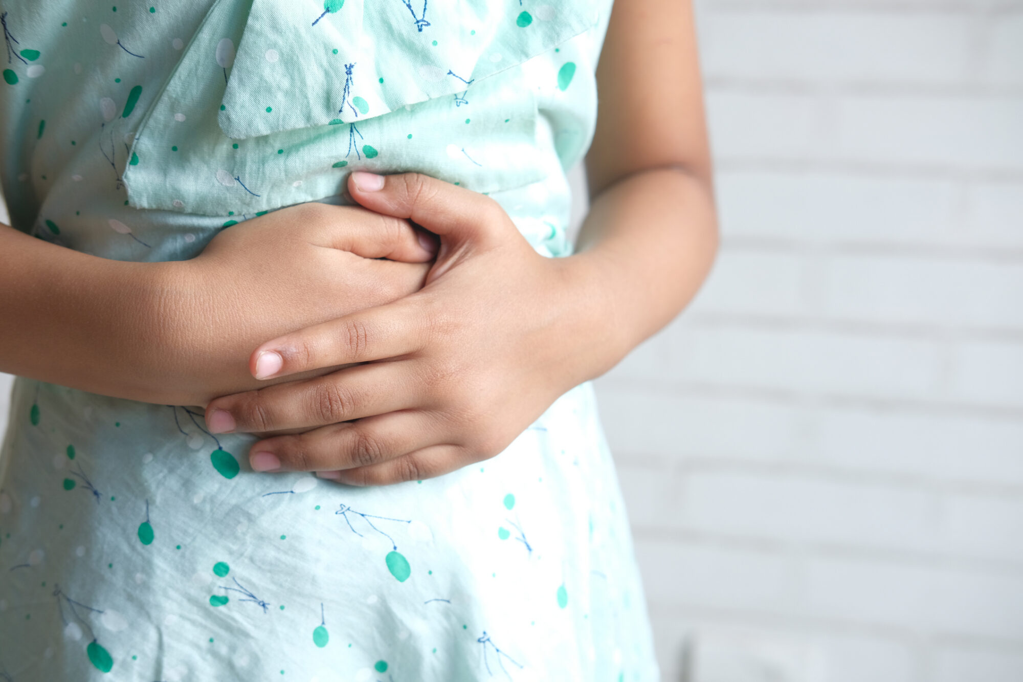Close up of a girl holding her stomach indicating indigestion.