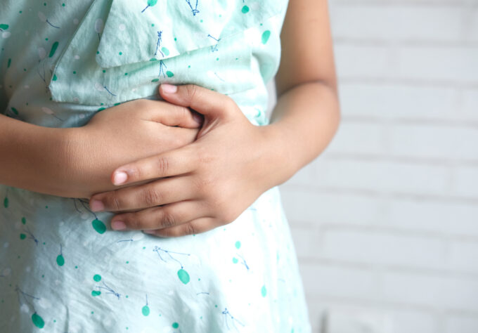 Close up of a girl holding her stomach indicating indigestion.