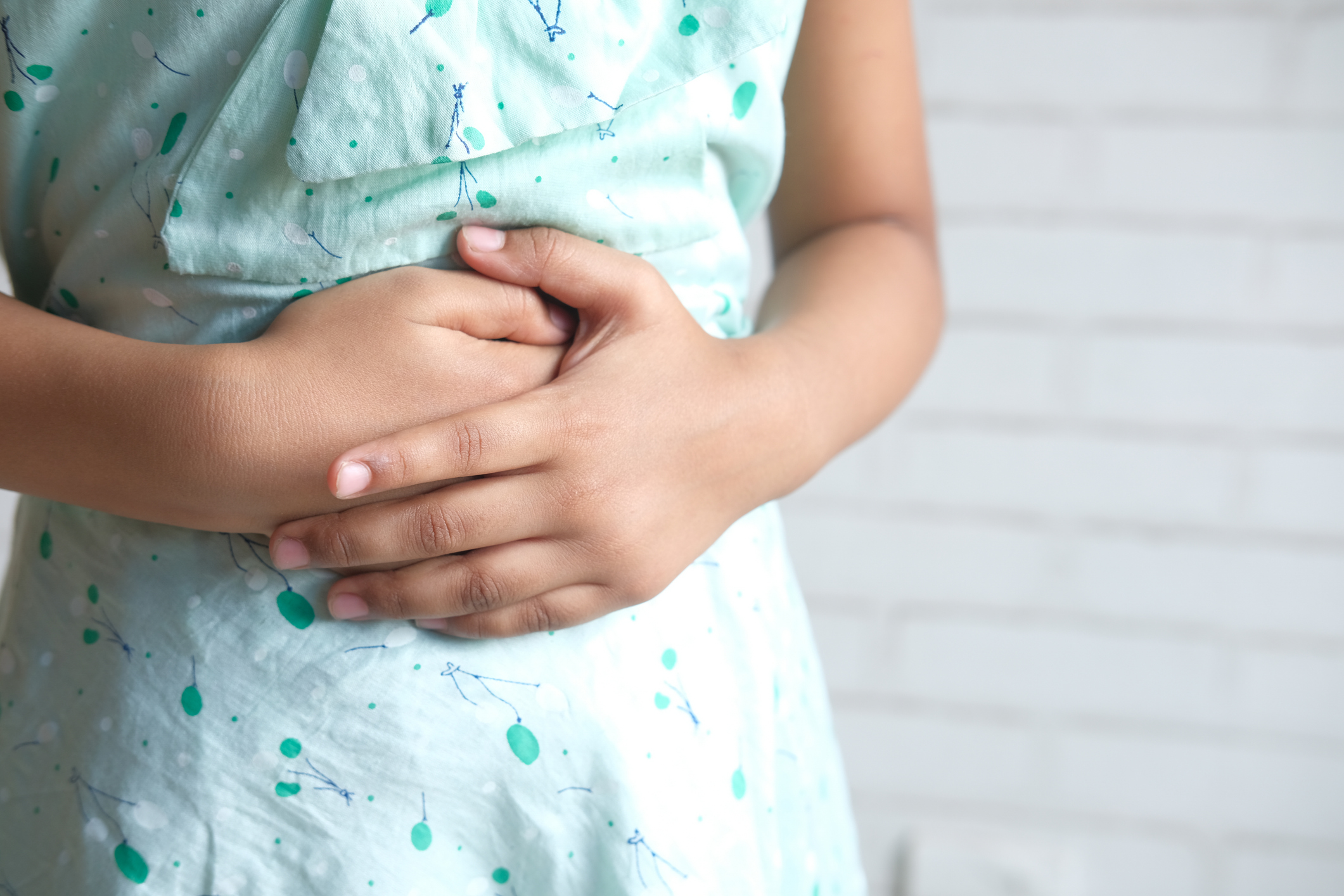 Close up of a girl holding her stomach indicating indigestion.