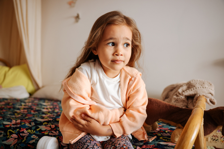 Photo of young girl having stomach pain in the house.