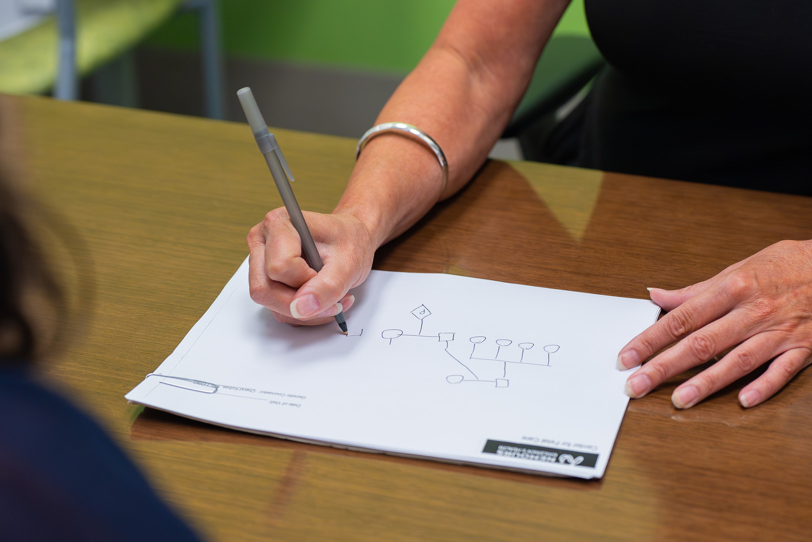 Image of genetic counselor working through a pedigree chart with a patient.