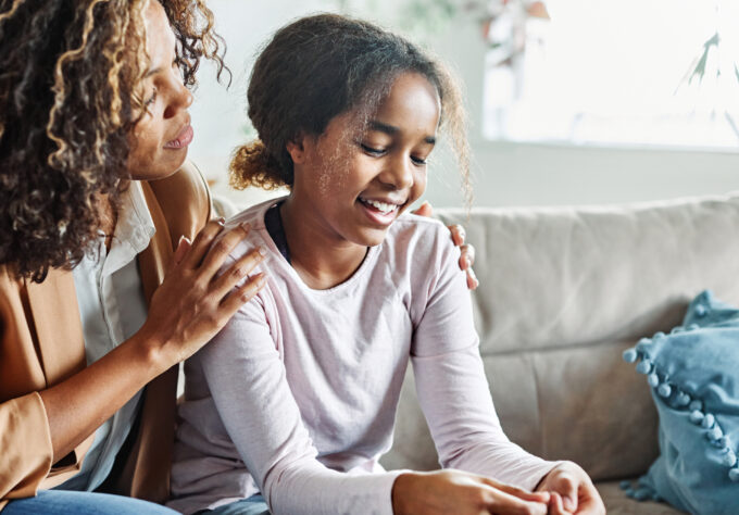 Adult sitting with a child on a couch, offering comfort and support at home