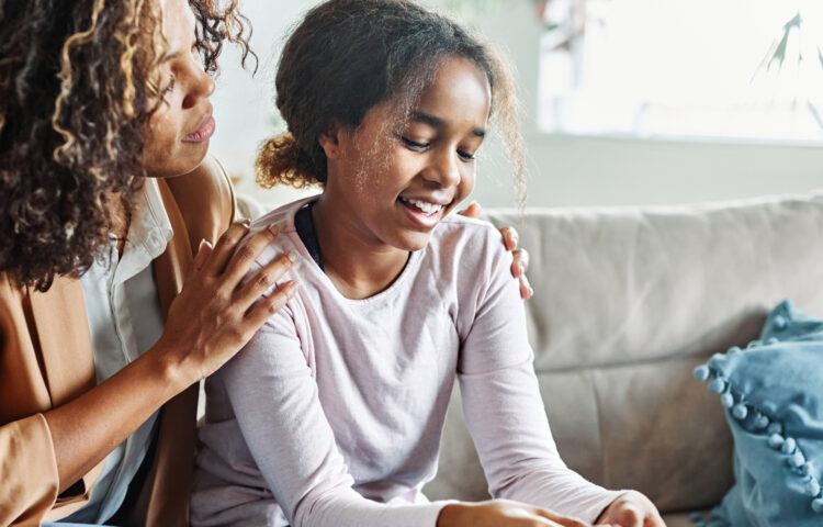 Adult sitting with a child on a couch, offering comfort and support at home