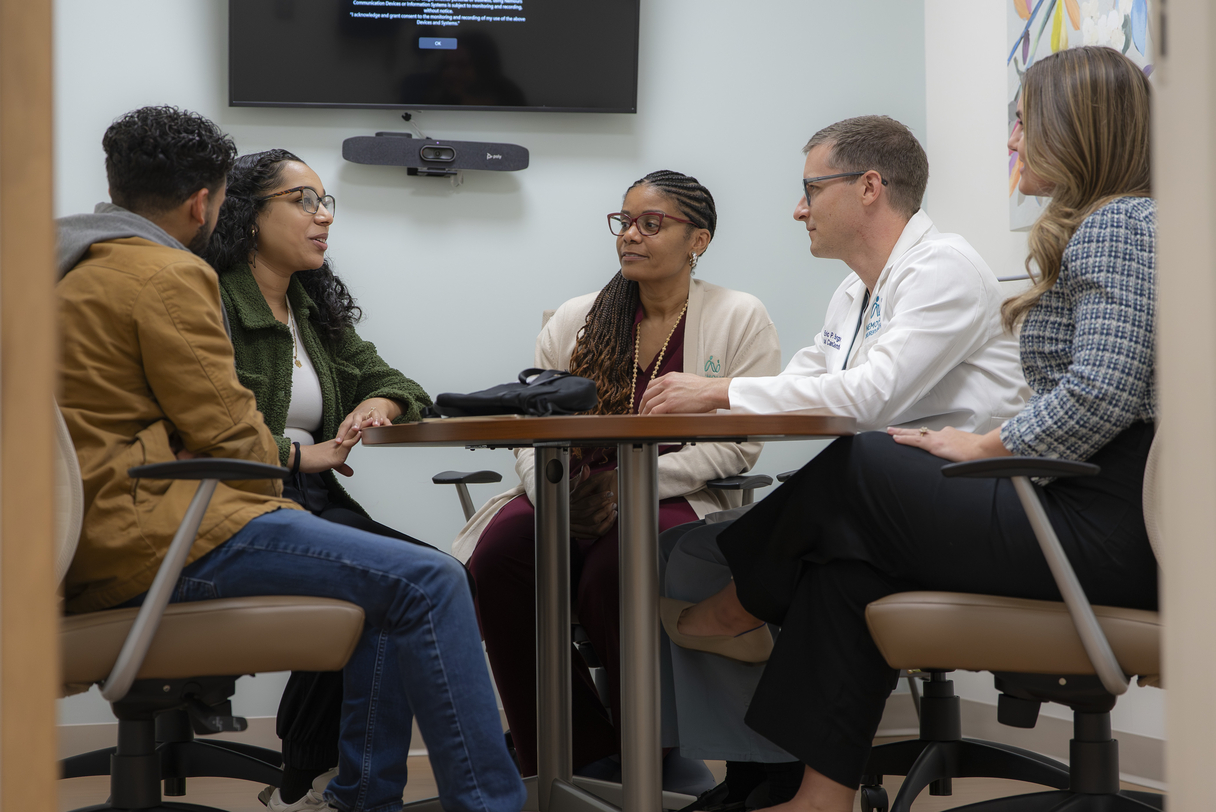 An expecting family meeting with members of a fetal care team during a consultation about prenatal diagnosis and treatment options.
