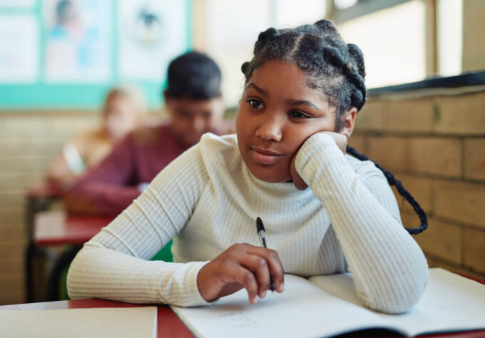 Student seated at a classroom desk working in a notebook during class.