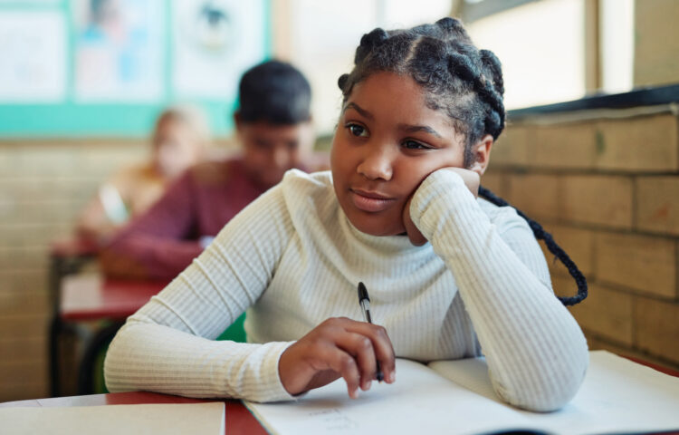 Student seated at a classroom desk working in a notebook during class.