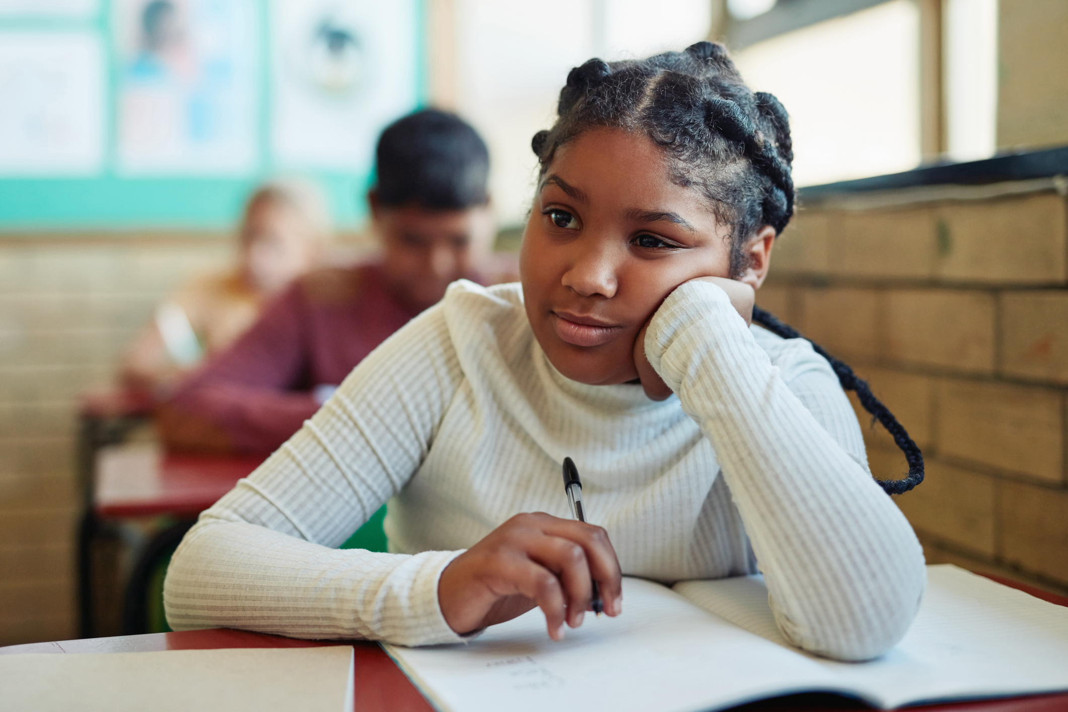 Student seated at a classroom desk working in a notebook during class.