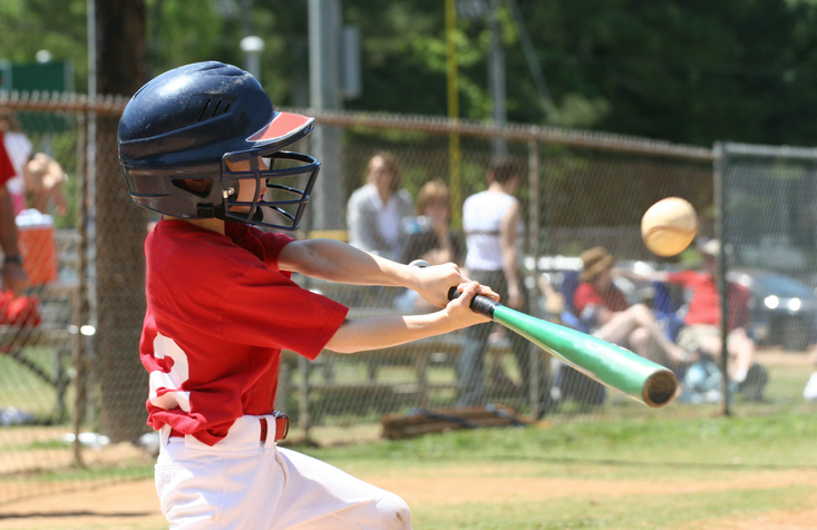 Young child swinging a baseball bat during a youth baseball game.