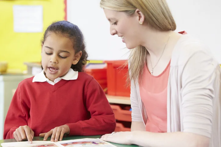 Child working on a reading activity with an educator in a classroom setting.
