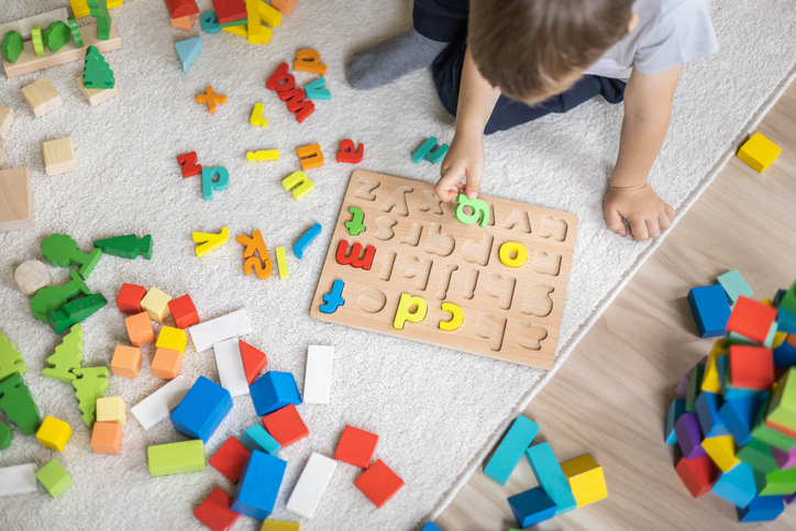 Child using alphabet puzzle pieces during a hands-on activity that supports letter recognition and early literacy development.