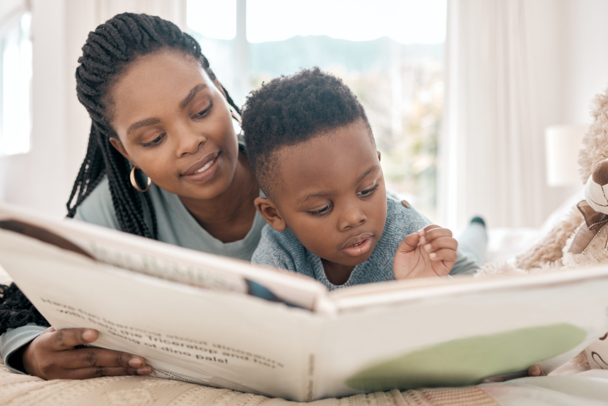 Adult and young child reading a picture book together at home, supporting early literacy and language development before kindergarten.