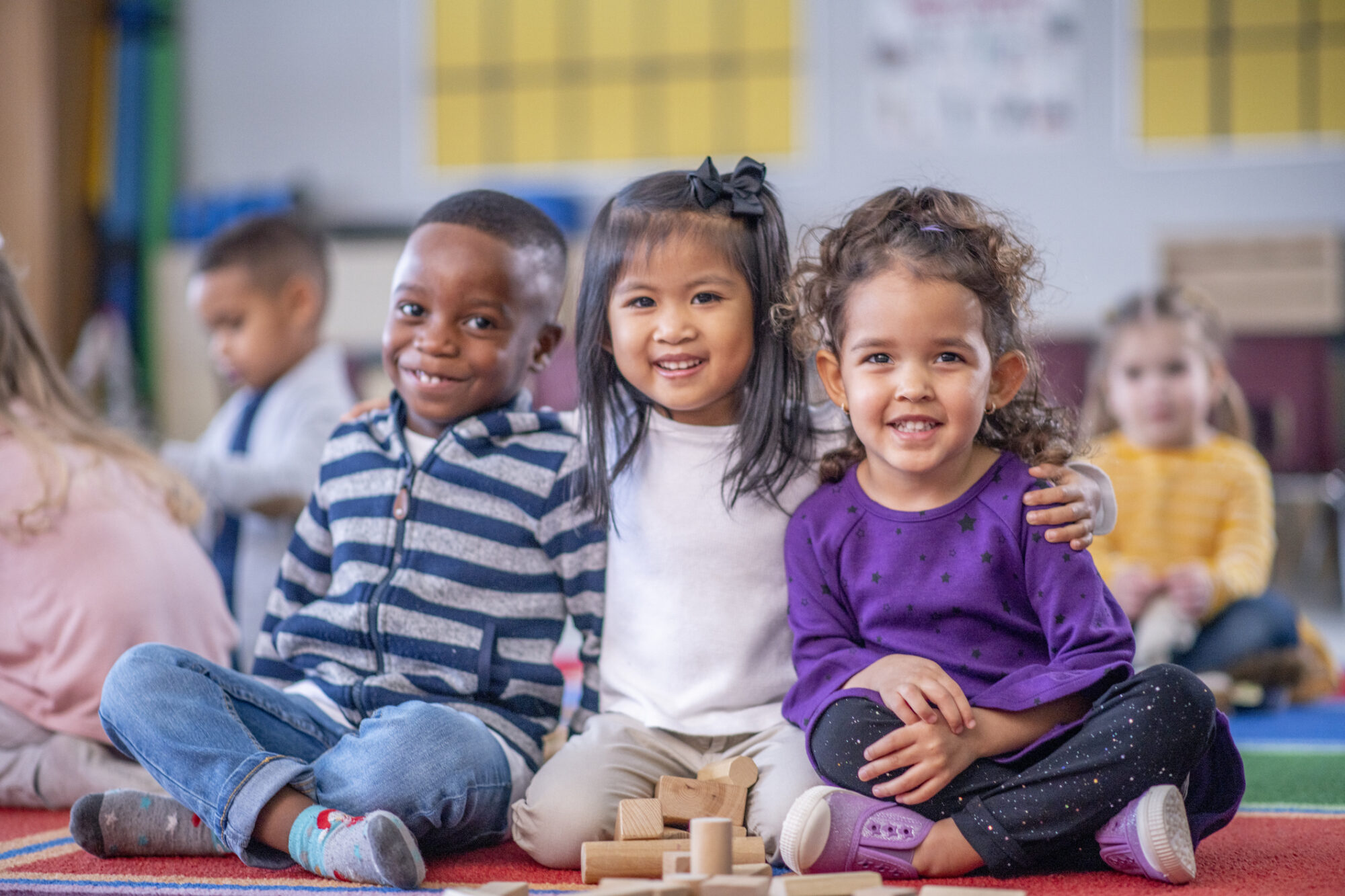 Young children seated together in an early learning classroom, participating in activities that support social, emotional, and educational development.