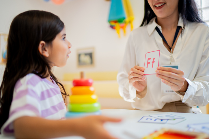 Educator showing a letter card during an early literacy activity focused on letter and sound recognition.
