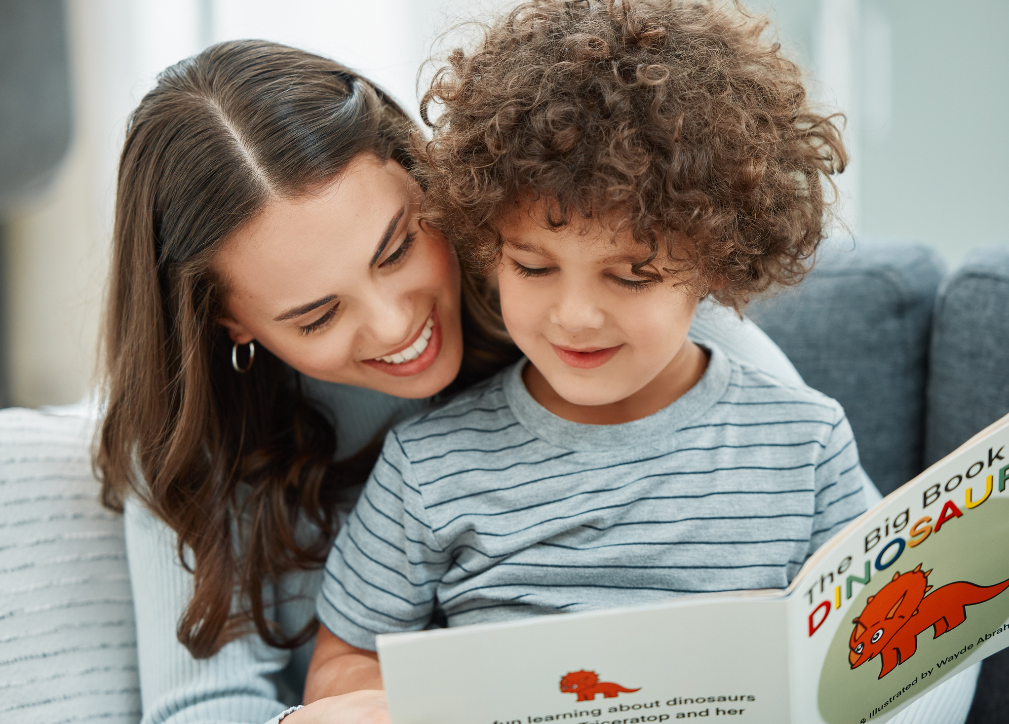 Adult reading a children's book with a young child while sitting together at home.