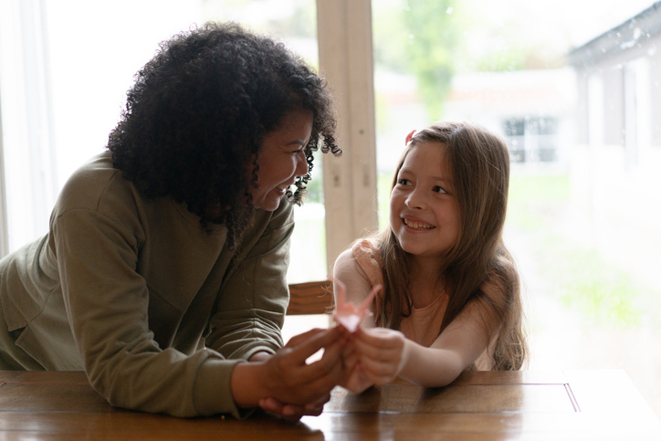 Adult and child spend time together at a table while talking and completing an activity at home.